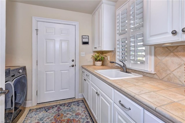 laundry room featuring washer / dryer, cabinet space, baseboards, and a sink