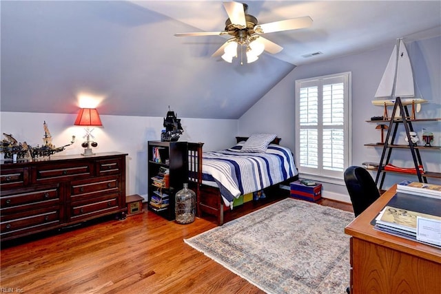 bedroom with a ceiling fan, lofted ceiling, wood finished floors, and visible vents