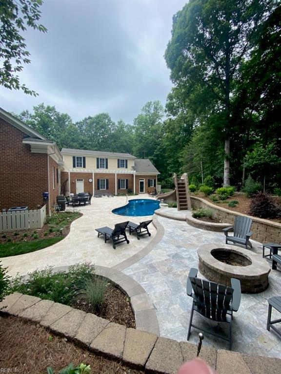 pool featuring a patio area, a water slide, and an outdoor fire pit