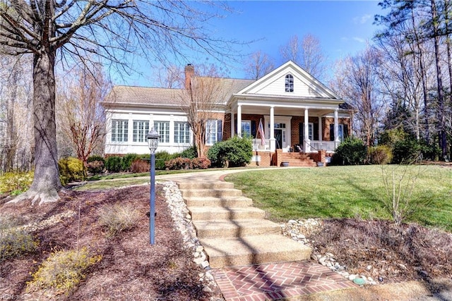 greek revival inspired property featuring a porch, brick siding, a front lawn, and a chimney