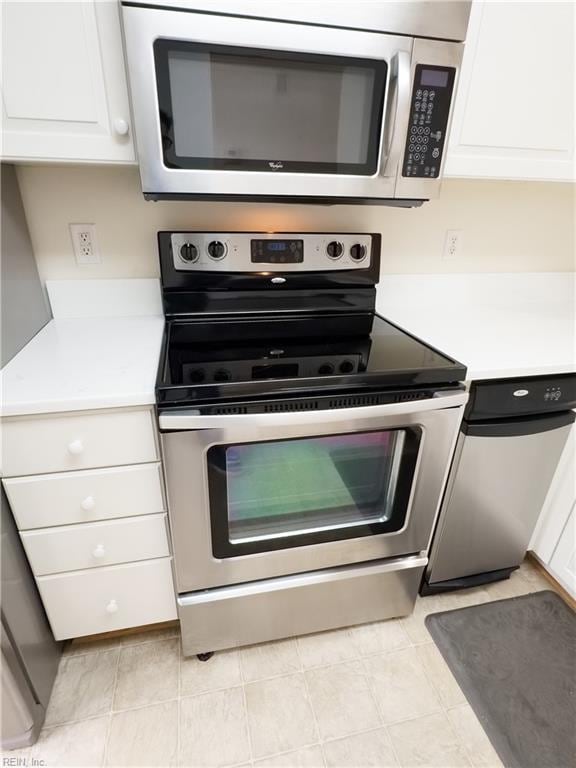 kitchen featuring stainless steel appliances, light tile patterned flooring, light countertops, and white cabinetry