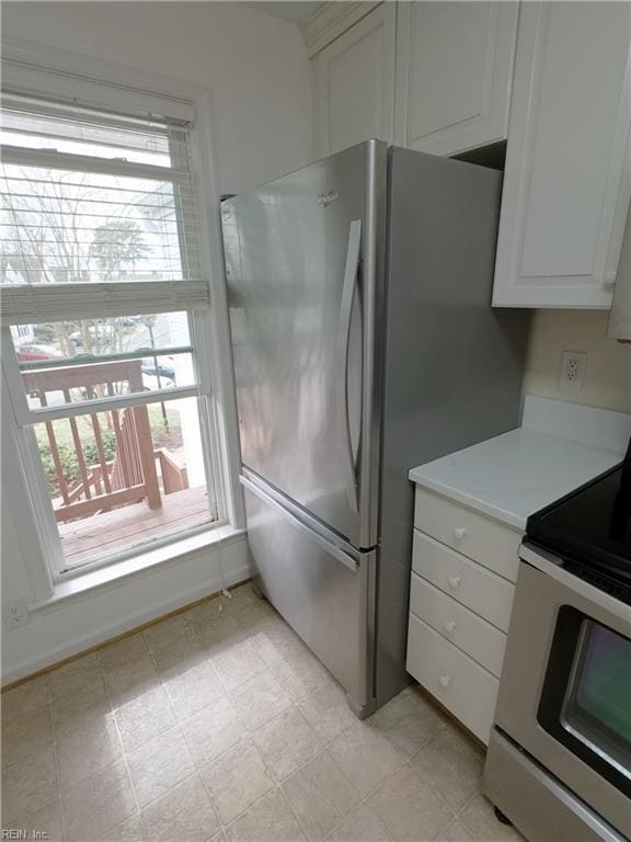 kitchen featuring light countertops, a healthy amount of sunlight, freestanding refrigerator, and range with electric cooktop