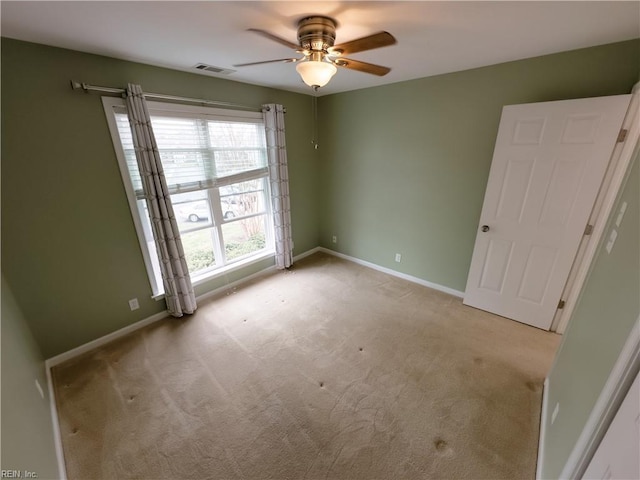 carpeted spare room with visible vents, ceiling fan, and baseboards