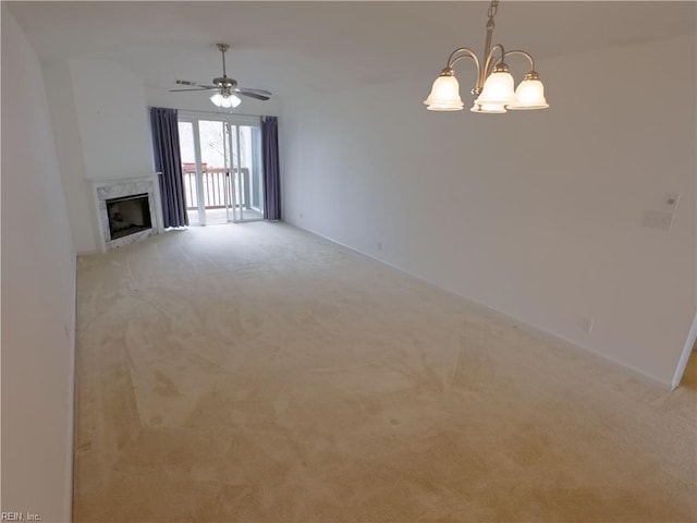 unfurnished living room featuring a premium fireplace, light carpet, and ceiling fan with notable chandelier