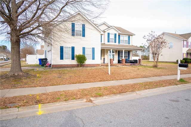 traditional-style house featuring covered porch and a front yard