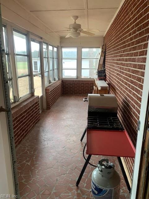 unfurnished sunroom with ceiling fan