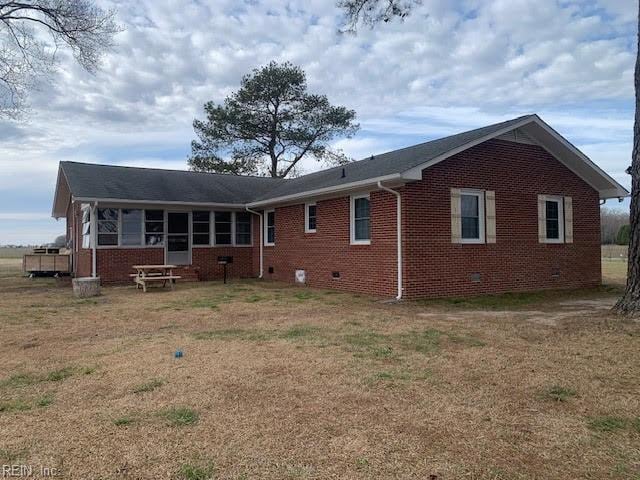 back of property with a lawn, brick siding, a sunroom, and crawl space