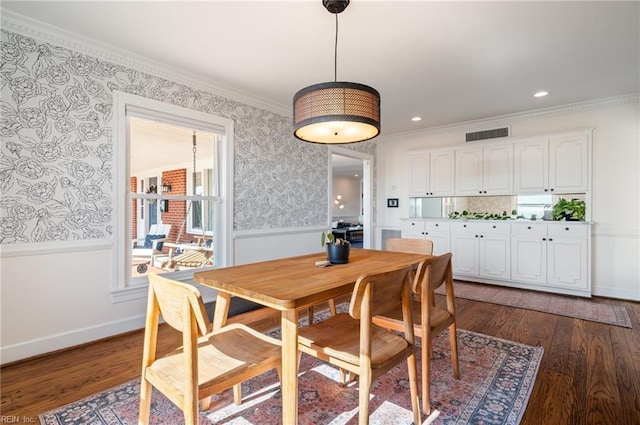 dining area with wallpapered walls, crown molding, and dark wood finished floors