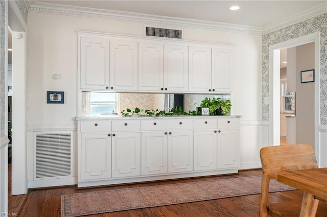 bar featuring wainscoting, visible vents, dark wood-style flooring, and ornamental molding