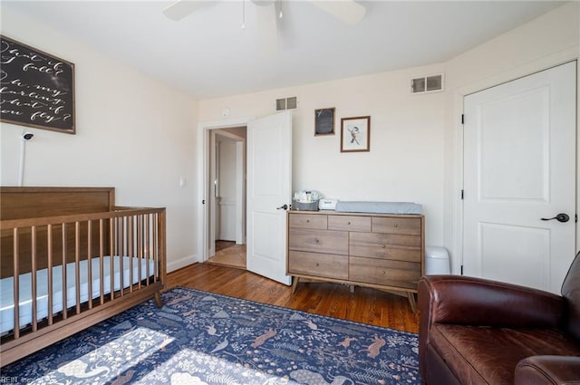 bedroom with ceiling fan, visible vents, baseboards, and wood finished floors