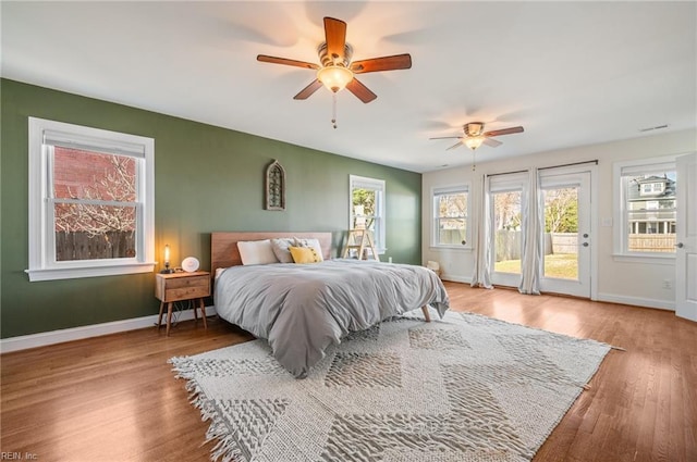 bedroom with ceiling fan, baseboards, wood finished floors, and access to exterior