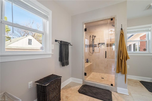 bathroom with a wealth of natural light, baseboards, a shower stall, and tile patterned flooring