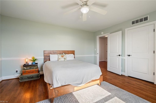 bedroom with ceiling fan, visible vents, baseboards, and wood finished floors