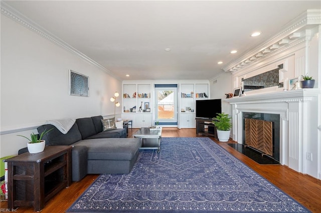 living area with a fireplace with flush hearth, wood finished floors, and ornamental molding