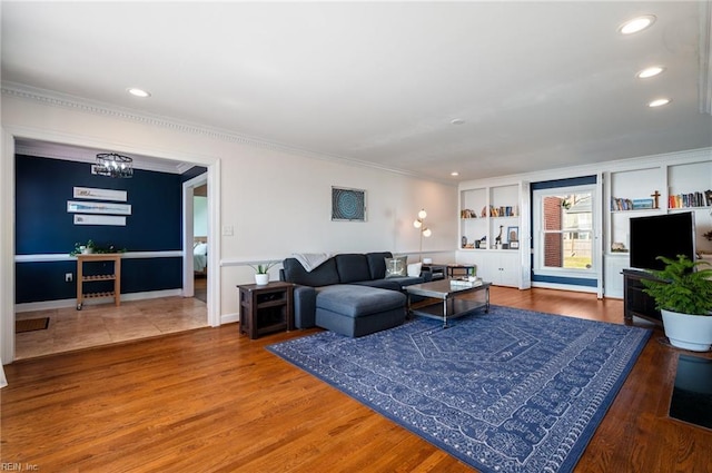 living room with baseboards, ornamental molding, recessed lighting, an inviting chandelier, and wood finished floors