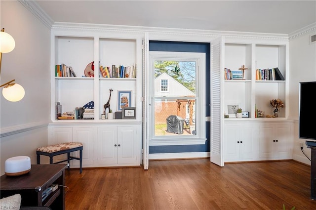 interior space with built in features, ornamental molding, visible vents, and wood finished floors