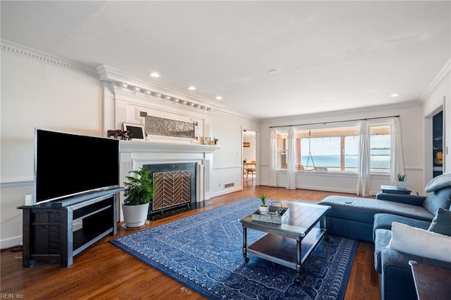 living room featuring visible vents, ornamental molding, a premium fireplace, recessed lighting, and wood finished floors