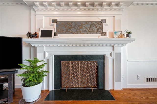 room details with a fireplace with flush hearth, visible vents, and wood finished floors