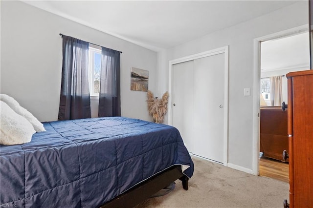 carpeted bedroom with multiple windows, baseboards, and a closet