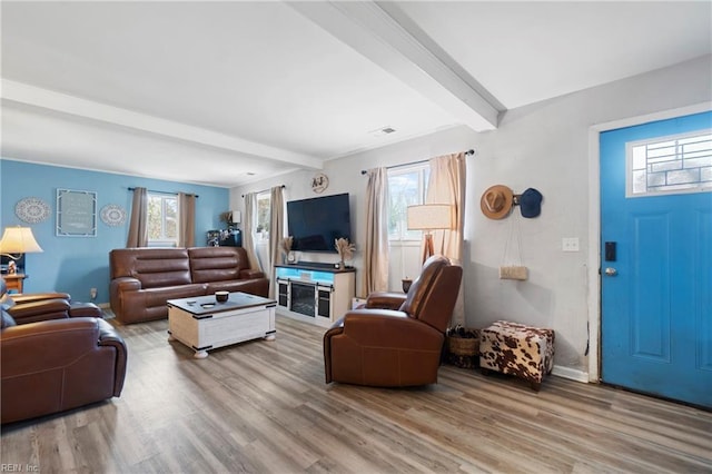 living room with beam ceiling, a healthy amount of sunlight, and wood finished floors