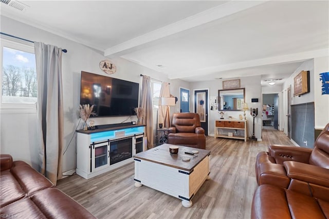 living room featuring beam ceiling, a fireplace, light wood-style floors, and visible vents