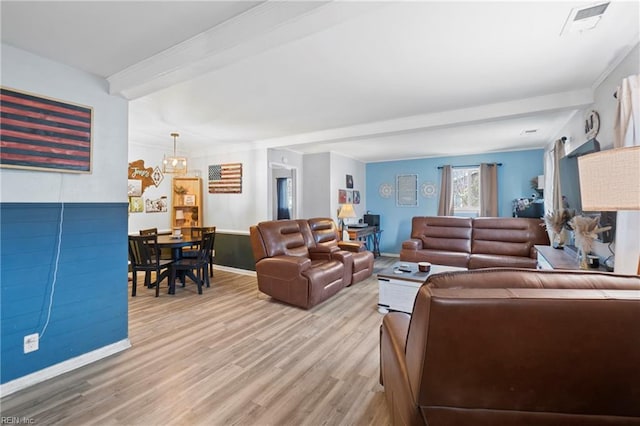 living room with beam ceiling, light wood-style flooring, and visible vents