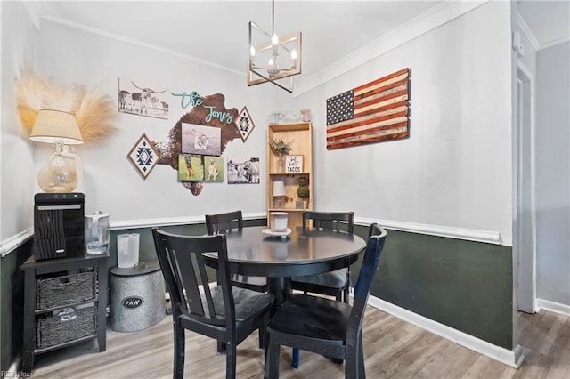 dining space featuring wood finished floors and crown molding