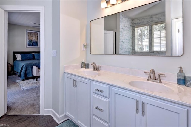 full bathroom with a sink, connected bathroom, wood finished floors, and double vanity