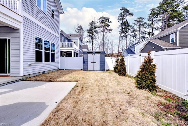 view of yard with a storage shed, an outdoor structure, a fenced backyard, and a patio