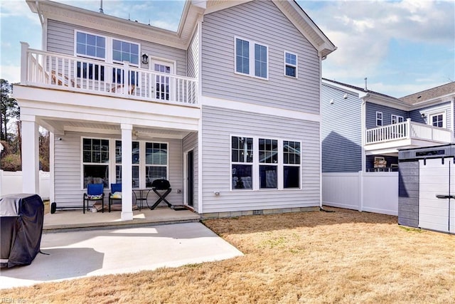 rear view of house with a yard, a patio, a balcony, and fence