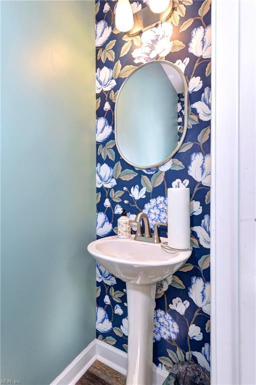 bathroom with wallpapered walls, baseboards, and wood finished floors