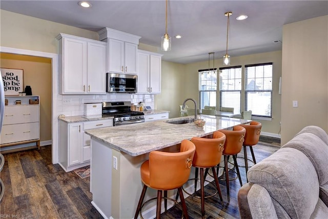 kitchen featuring a sink, dark wood-style floors, stainless steel appliances, white cabinets, and decorative backsplash