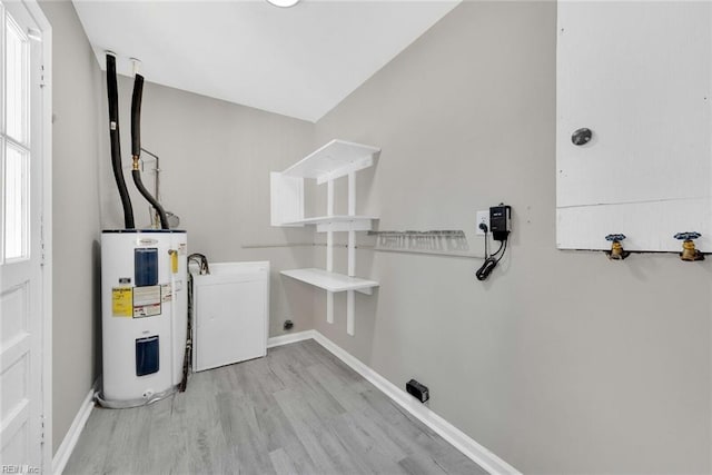 laundry area with laundry area, wood finished floors, water heater, and baseboards