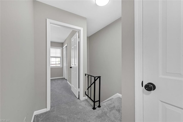 corridor with an upstairs landing, carpet flooring, and baseboards