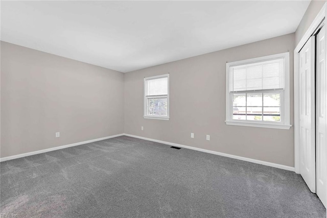 unfurnished room featuring a healthy amount of sunlight, carpet, and baseboards