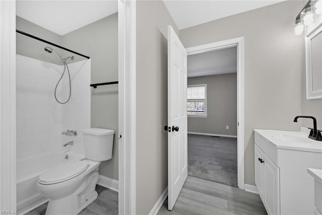 full bathroom with toilet, wood finished floors, shower / washtub combination, baseboards, and vanity