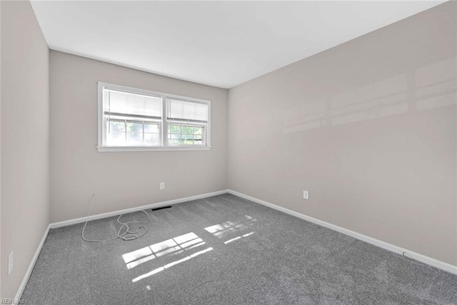 carpeted spare room with visible vents and baseboards