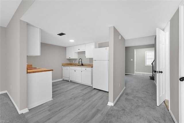 kitchen with visible vents, baseboards, light countertops, white appliances, and a sink