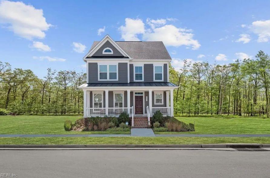 view of front of home featuring metal roof, covered porch, a front lawn, and a standing seam roof