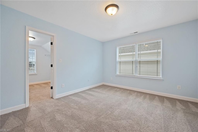 empty room with baseboards, visible vents, carpet floors, and a textured ceiling