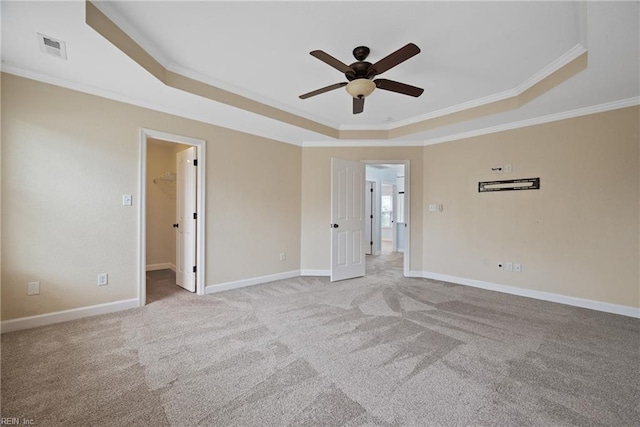 carpeted spare room with a ceiling fan, baseboards, visible vents, a tray ceiling, and ornamental molding