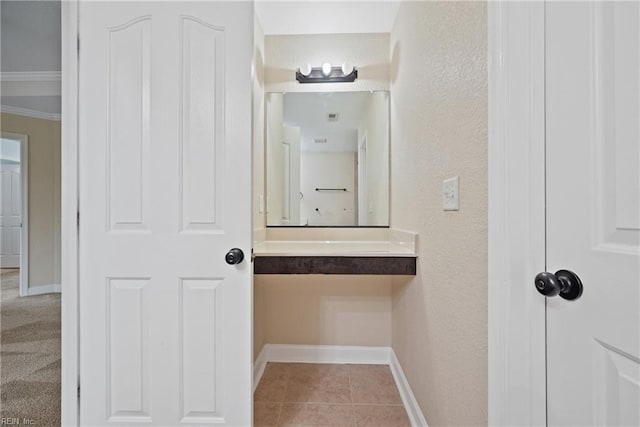 bathroom with tile patterned flooring, vanity, baseboards, and a textured wall