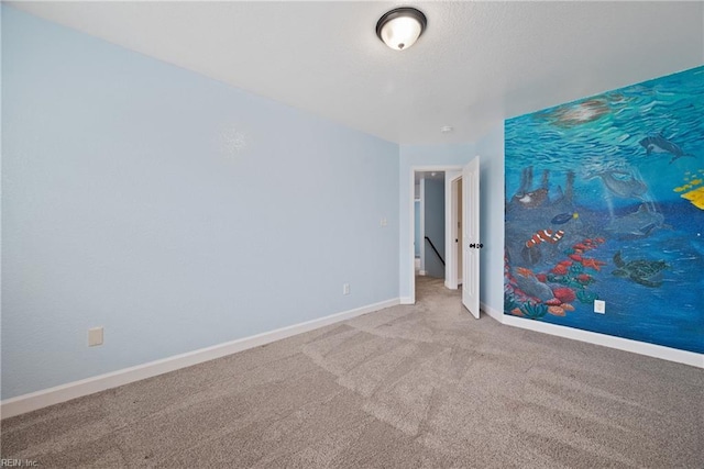 carpeted spare room featuring baseboards