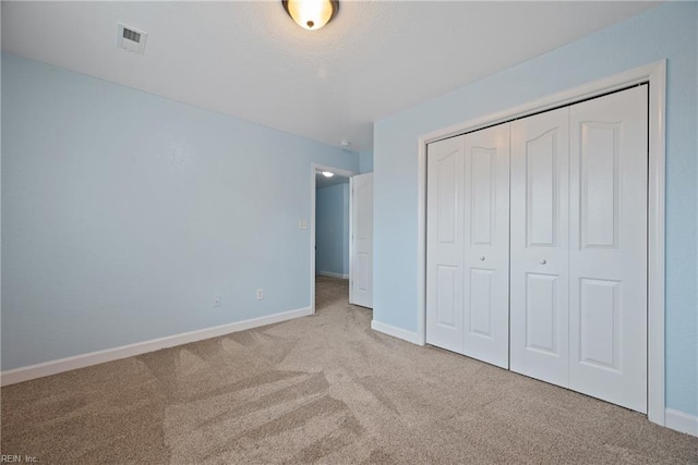 unfurnished bedroom with carpet flooring, baseboards, visible vents, and a closet