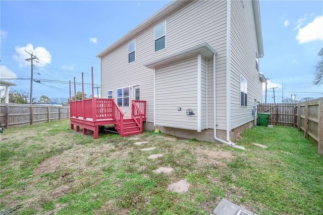 back of property with a yard, a wooden deck, and a fenced backyard