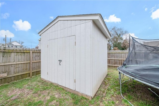 view of shed with a trampoline and a fenced backyard