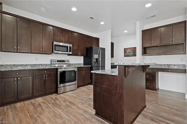 kitchen with light wood-type flooring, visible vents, dark brown cabinetry, and appliances with stainless steel finishes