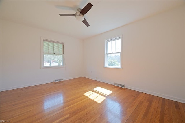 spare room with a ceiling fan, light wood-style flooring, baseboards, and visible vents