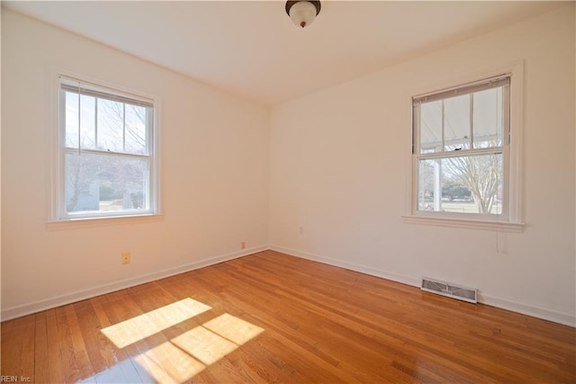 empty room featuring visible vents, baseboards, and light wood-style floors