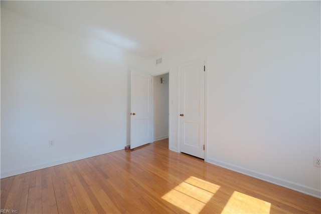 unfurnished room with visible vents, light wood-style floors, and baseboards